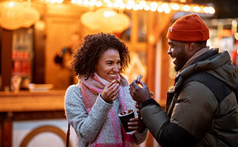 a man and a woman enjoying cocoa outside in cold weather