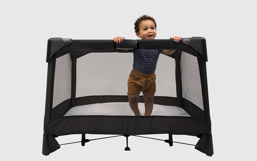 baby standing up in a travel cribe